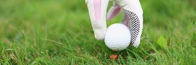 Hand im Golfhandschuh legt Ball auf Golfabschlag