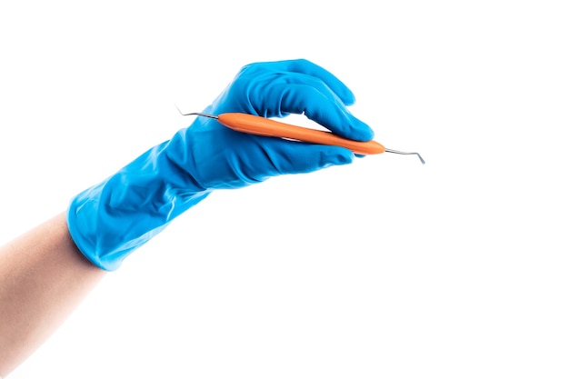 Hand in blauem Handschuh mit zahnmedizinischem Metallstab isoliert auf weißem Hintergrund