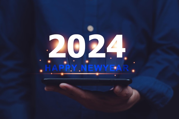 Hand in der Hand Mobiltelefon senden Sie eine Nachricht Glückliches Neujahr 2024