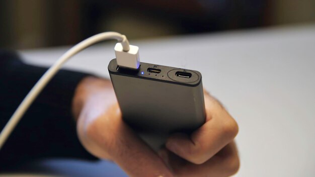 Hand in der Nähe, die ein USB-Kabelladegerät in ein tragbares Powerbank-Medium steckt