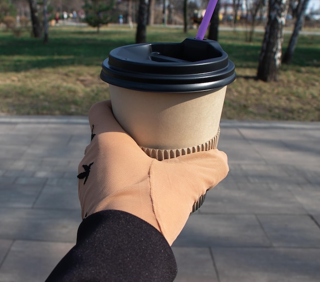 Hand in einem Maschenhandschuh hält eine Papiertasse Kaffee