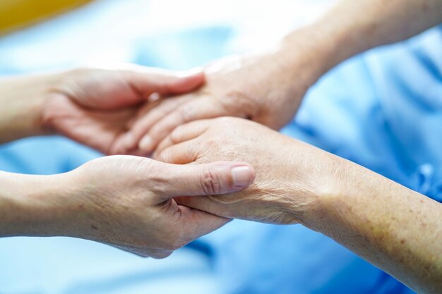 Foto hand in hand berühren asiatische ältere oder ältere alte dame patientin mit liebevoller pflege hilft, zu ermutigen und mitgefühl auf der krankenhausstation zu fördern gesundes starkes medizinisches konzept