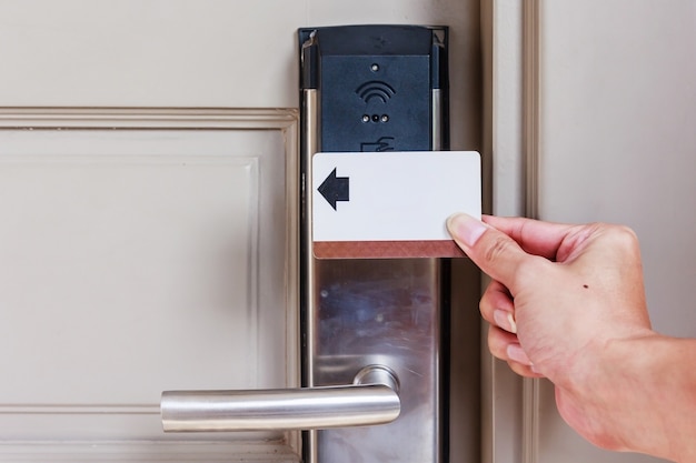 Hand junger Mann, der eine Keycard vor dem elektronischen Sensor eines Raumes hält