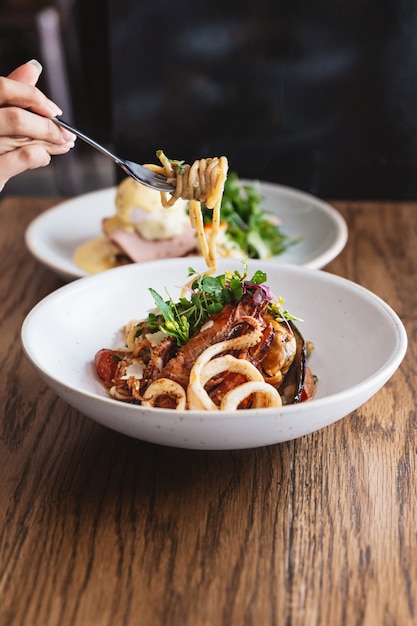 Hand kneifen Spaghetti Meeresfrüchte und mit einer Gabel angehoben: Spaghetti mit Garnelen, Tintenfischen, in Olivenöl gekochten Muscheln, Chilischoten und Knoblauch.