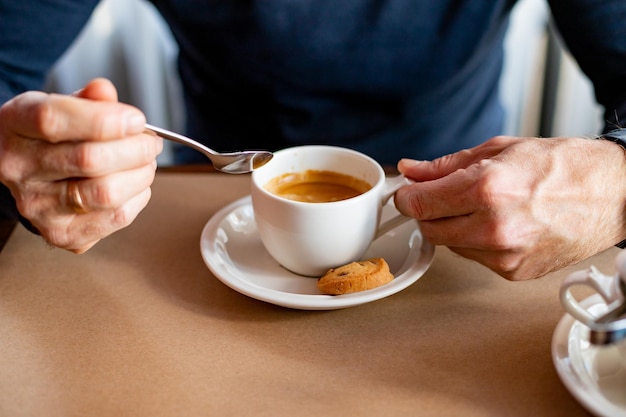 Hand legt einen Zuckerwürfel in die Kaffeetasse Leckeres Morgengetränk mit Keks und Zucker