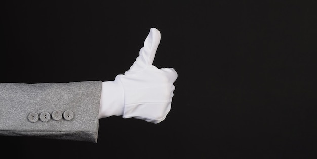 Hand mag Handzeichen und trägt Stoffhandschuhe oder Baumwollhandschuh mit Anzug auf schwarzem Hintergrund