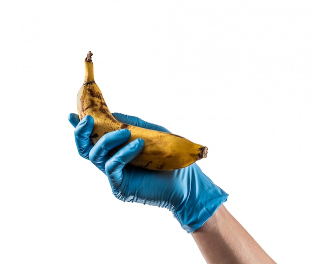 Hand mit blauem Latexhandschuh, der eine Banane hält