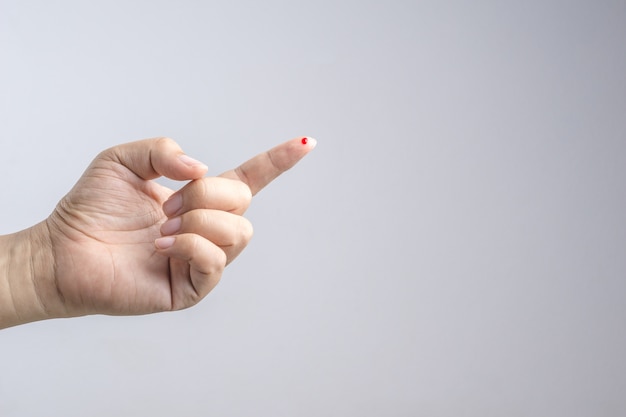 Hand mit Blutstropfen am Finger von der Nadel für das Probeprüfen