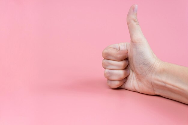 Hand mit Daumen nach oben auf einem rosa Hintergrund aus nächster Nähe. Platz kopieren. Banner.