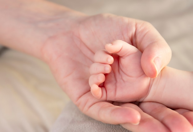 Hand mit den Fingern einer neugeborenen Baby- und Mutterhand