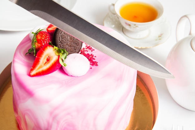 Hand mit einem Messer, um den Kuchen auf Party Geburtstagstorte köstlichen Biskuit rosa Fondantkuchen zu schneiden