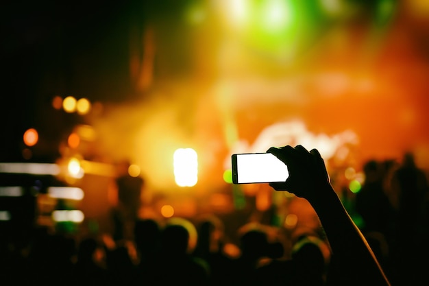 Hand mit einem Smartphone nimmt die Live-Konzertshow des Live-Musikfestivals auf der Bühne auf