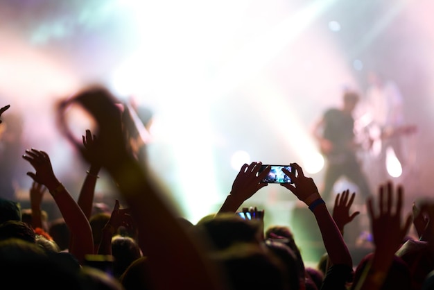 Foto hand mit einem telefon nimmt live-musikfestival auf menschen, die mit smartphones fotos von konzerten machen