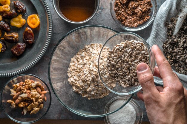 Hand mit einer Schüssel Samenzutaten für das Müsli und der Rührschüssel