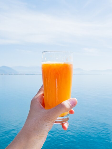 Hand mit frischen leckeren frisch gepressten Saft von reifen Orangen im Glas.