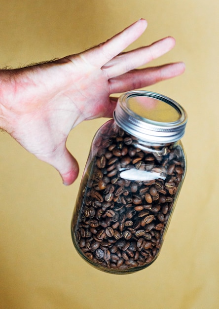 Hand mit Glastopf voller Kaffeebohnen