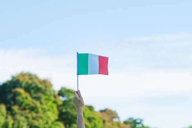 Hand mit italienischer Flagge auf Naturhintergrund Nationalfeiertag Tag der Republik Festa della Repubblica und fröhliche Feierkonzepte