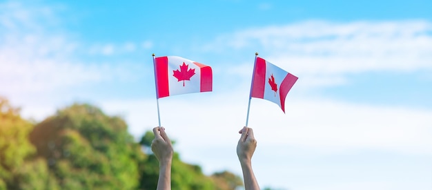 Hand mit Kanada-Flagge auf blauem Himmelshintergrund Canada Day und fröhliche Feierkonzepte