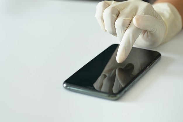 Foto hand mit medizinischem handschuh, der smartphone im selektiven fokus berührt