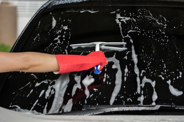 Hand mit Rakel zum Waschen der Windschutzscheibe des Autos