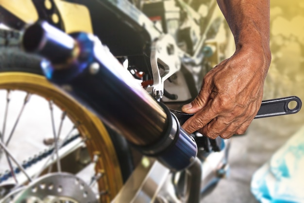 Hand mit Schlüssel, professioneller Mechanikerreparatur und Änderungen am Motorrad