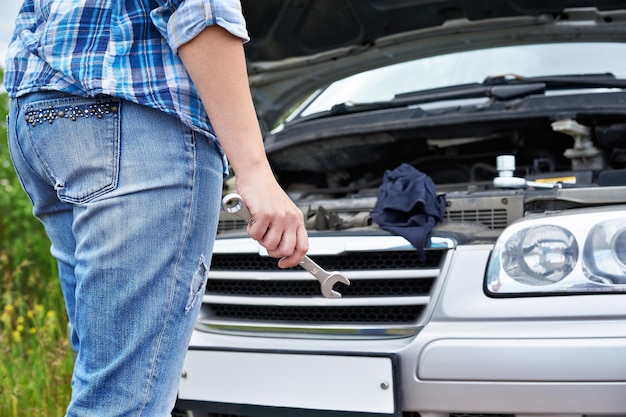 Hand mit Schraubenschlüssel und Auto