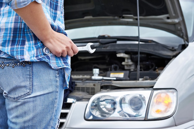 Hand mit Schraubenschlüssel und Auto