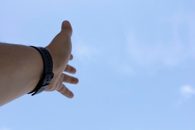 Hand mit Smartwatch auf dem Hintergrund des Himmels