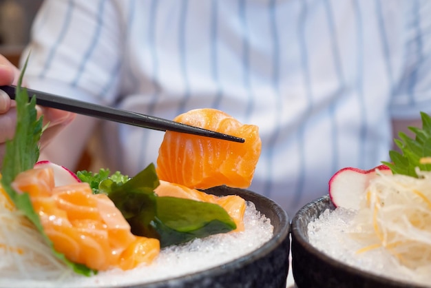 Hand mit Stäbchen halten Lachs-Sashimi japanisches Essen