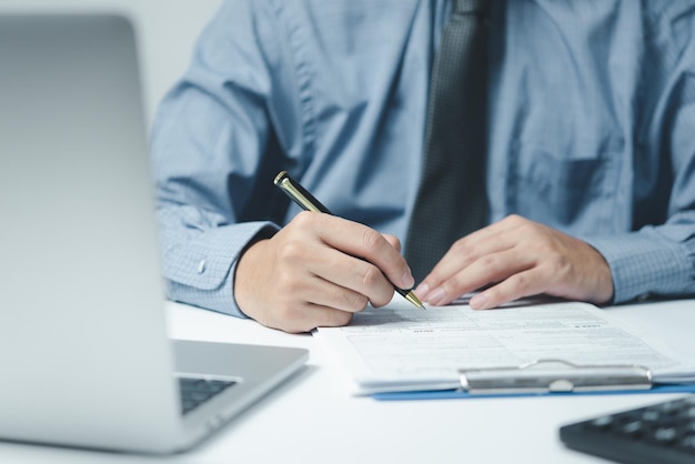 Hand mit Stift schreiben Papierkram Geschäftsdokument Finanzinvestition oder Unterschrift Vertrag Job und Versicherung auf dem Schreibtisch