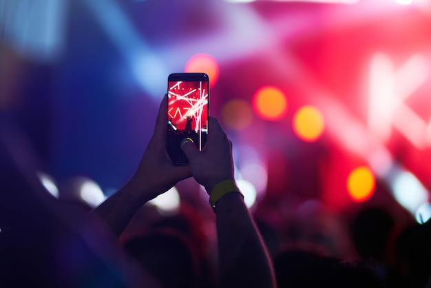 Hand mit Telefonaufzeichnungen Live-Musikfestival Menschen, die während des Konzerts mit dem Smartphone fotografieren