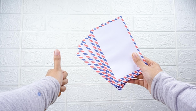 Hand mit THR-Umschlag an weißer Wand THR ist Urlaubsgeld an Eid alFitr- oder Lebaran-Tagen