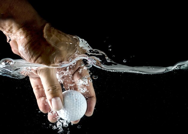 Hand nehmen Golf Ball plantschen in Wasser.