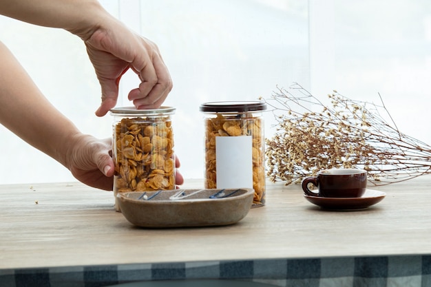 Hand öffnet die Plastikdose Asiatische süße Snacks leckere gemischte Cornflakes-Modell für Logo