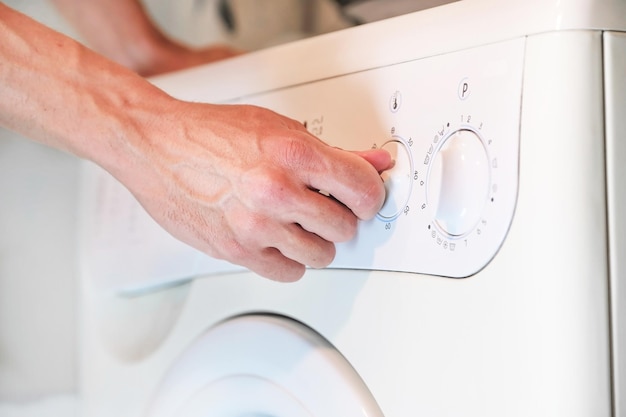 Hand schaltet den Temperaturregler an der Waschmaschine