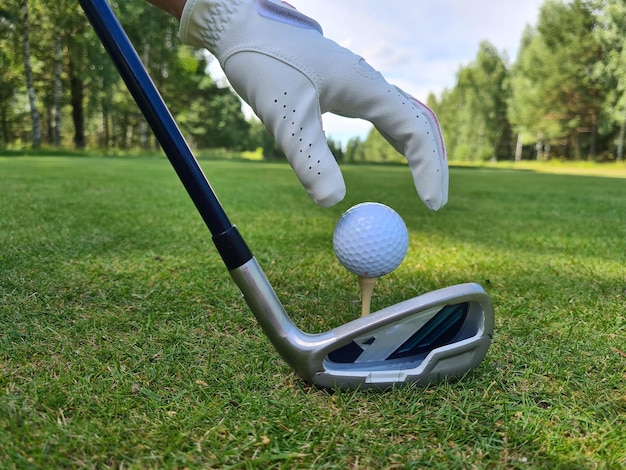 Hand setzen Golfball auf Tee mit Schläger auf dem Golfplatz