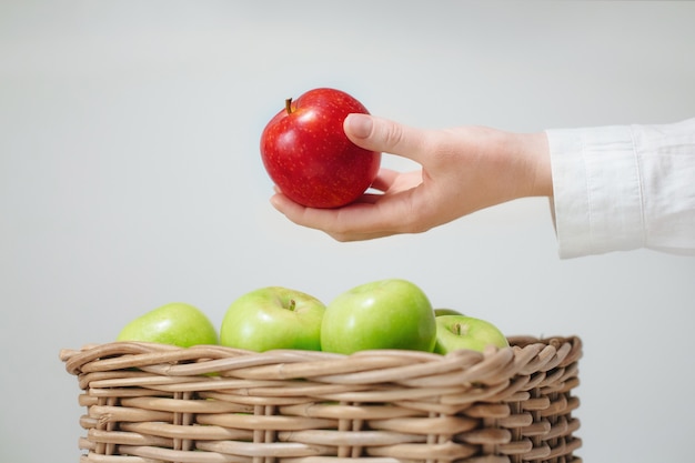 Hand über Korb mit grünen Äpfeln und rotem