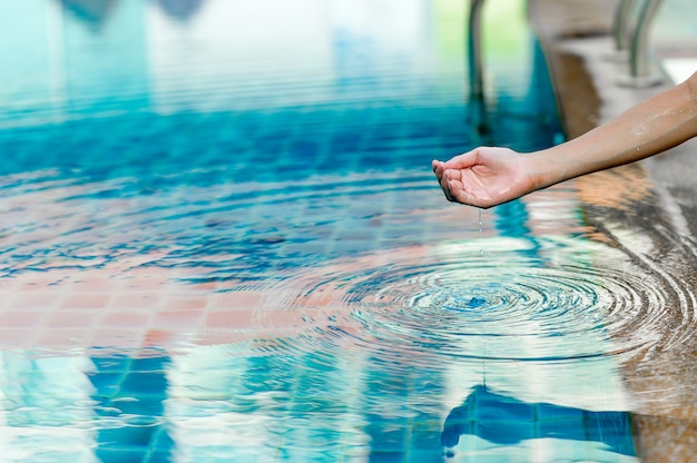 Hand und wasser berühren das blaue wasser. um das konzept des trinkwassers mit textfreiraum aufzufrischen.