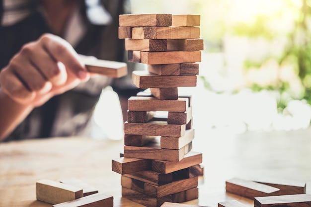 Hand von den Wirtschaftlern, die hölzernen Block auf den Turm setzen und ziehen