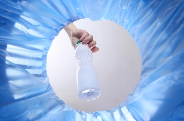 Hand wirft Plastikflasche in Mülleimer mit Paket Innenansicht