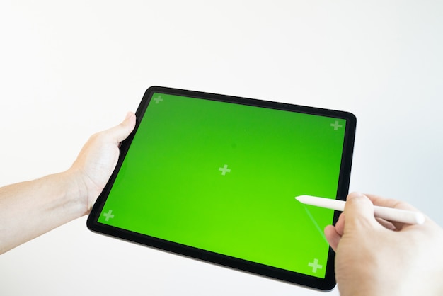 Hand zeichnet einen Bleistift auf eine Tablette mit einem Chromakey auf dem Bildschirm.