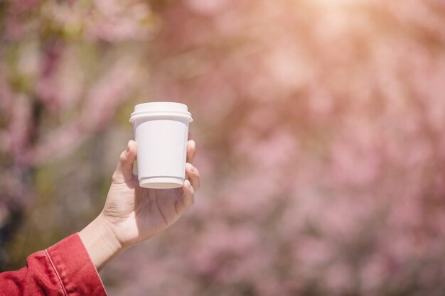 Hand zeigt eine weiße Tasse heißen Kaffees