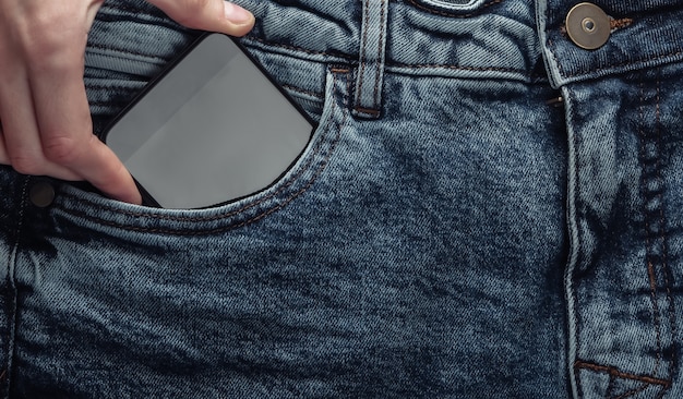 Hand zieht Smartphone aus der vorderen Jeanstasche