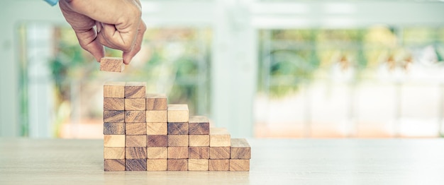 Handarbeit beim Platzieren eines hölzernen Blockturmstapels in einer Pyramidentreppe