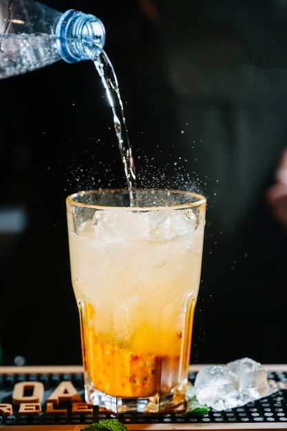 Handbarmixer machen Cocktail. Cocktail haben Orangen- und Minzblätter.