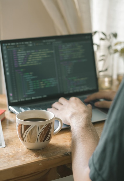 Handeingabetastatur auf Laptoparbeit von Heimcode-Programmierungsfreiberufler mit Kaffee