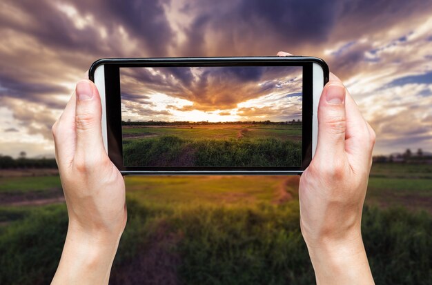 Handfrau, die Foto bei Sonnenuntergang macht.