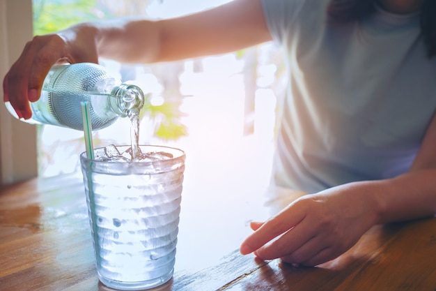 Handfrauen, welche die Glasflasche Wasser halten