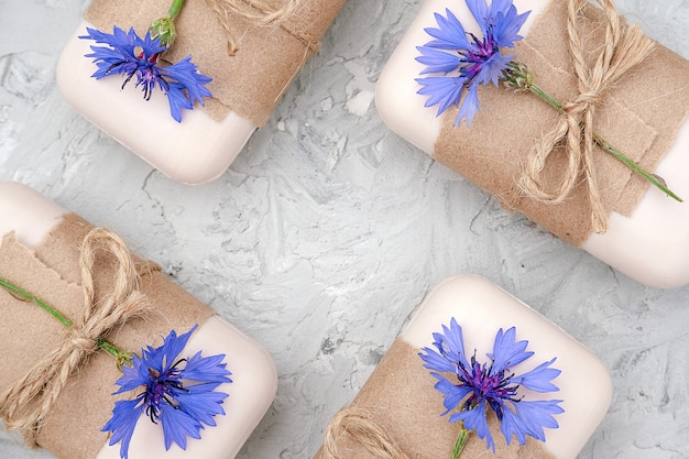 Handgearbeitetes Naturseifenset, verziert mit Kraftpapier, Geißel und blauen Blumen. Bio-Kosmetik-Konzept.