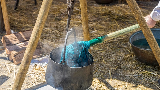 Handgefärbtes Färben von Stoffen und Wolle in einem Kessel mit farbigen Farbstoffen auf einem mittelalterlichen Jahrmarkt in Spanien